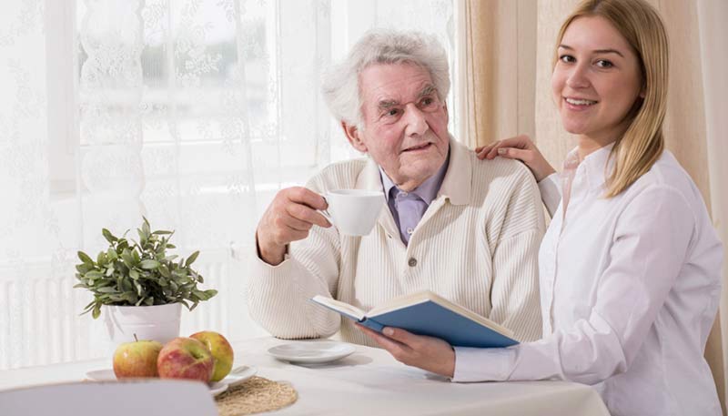 older man sitting at table working on advanced care planning with medical professional